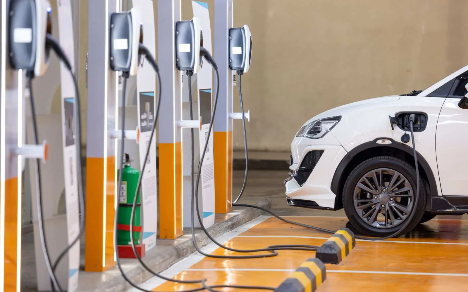 A row of AC EV chargers at a covered station in Pakistan with a white SUV plugged in
